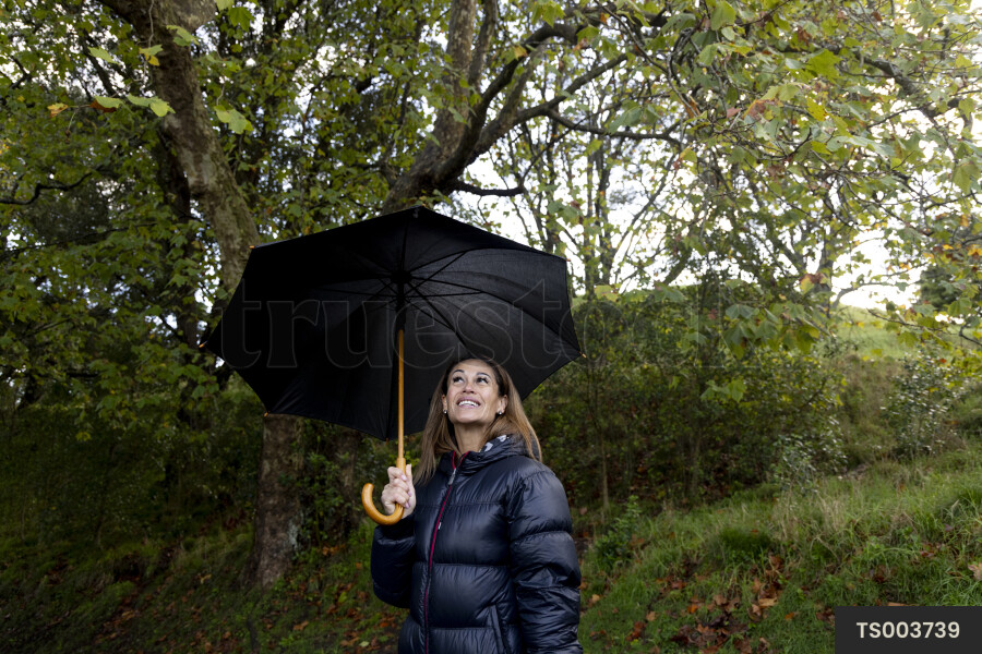 Woman in puffer jacket with umbrella in park
