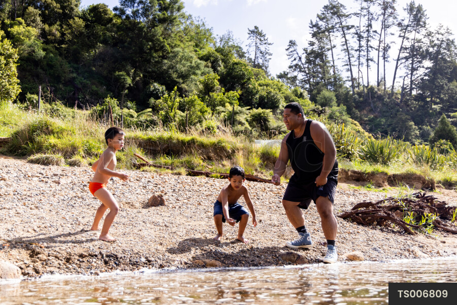 Man playing with his children by river