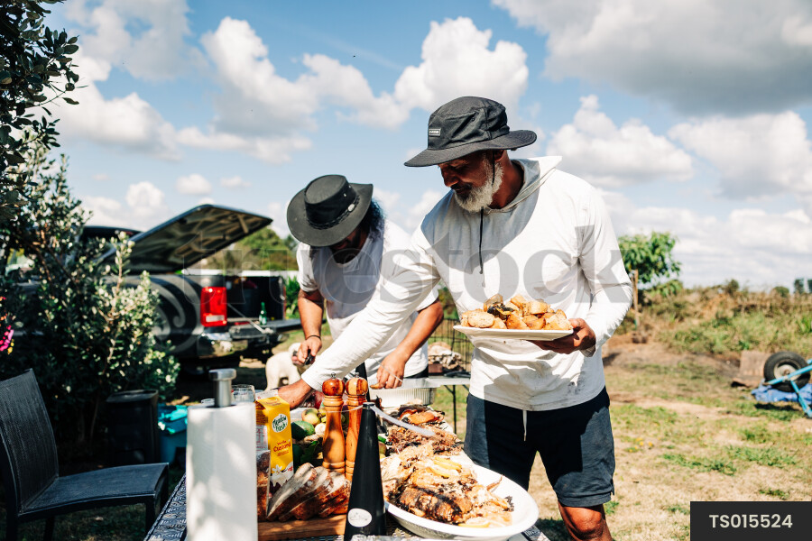 Father and son serving food on table in back yard