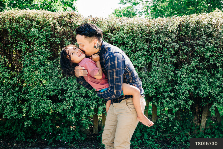 Māori father hugging son in backyard