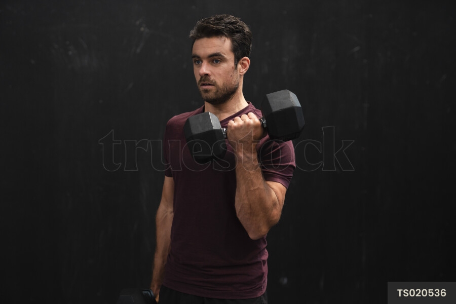 Young man lifting dumbbell in gym
