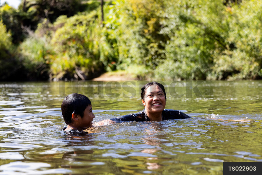 Smiling boy and girl swimming in river