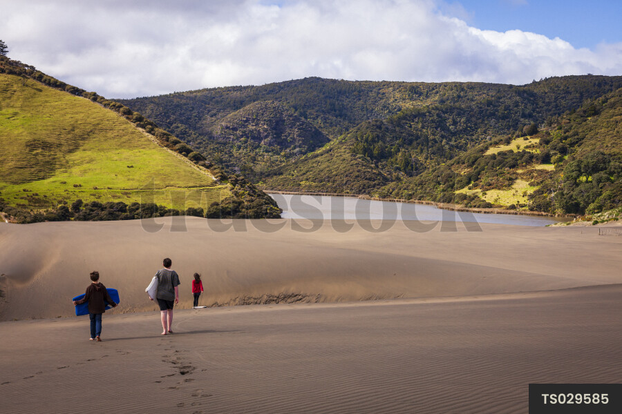 Children playing on sand dunes at Bethells Beach