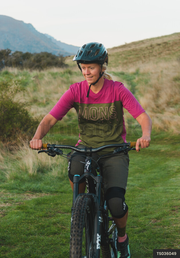 Woman mountain biking with protective clothing in field