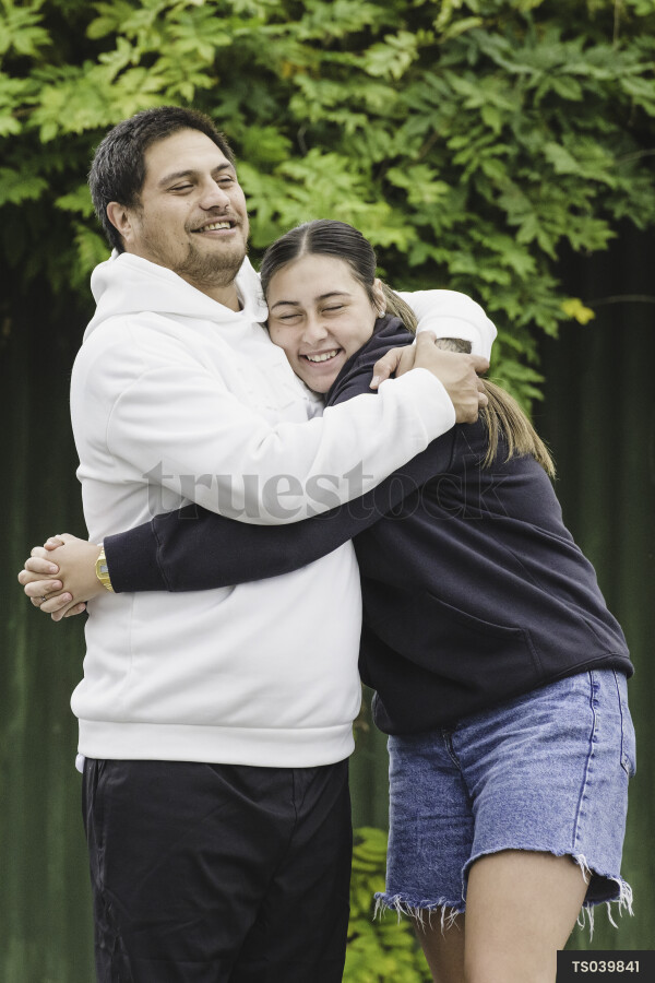 Man hugging his teenage daughter