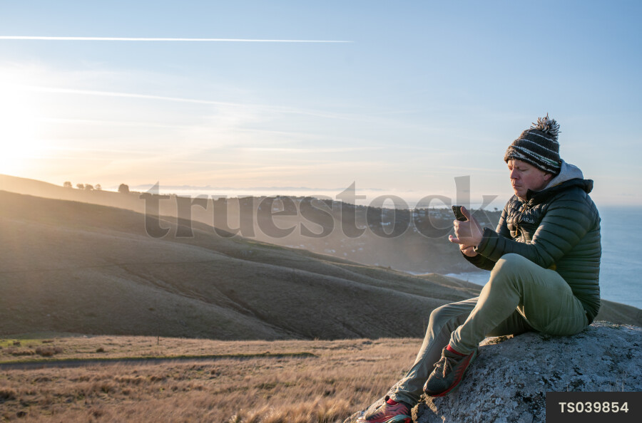 Man with smartphone on rock