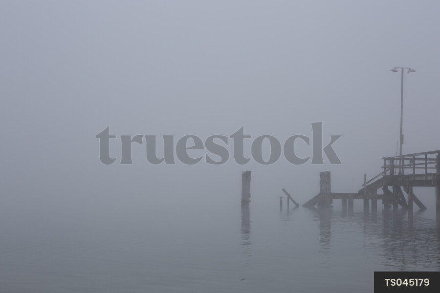 Wharf on water's edge in fog