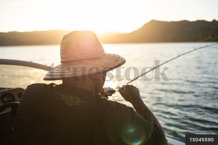 Man fishing from boat at sunset