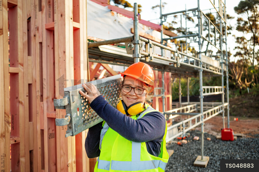 Woman carrying scaffolding in construction site