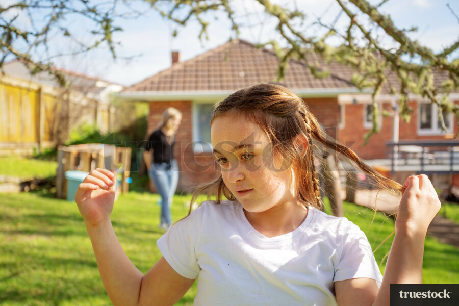Young Girl Playing with Hair in Backyard