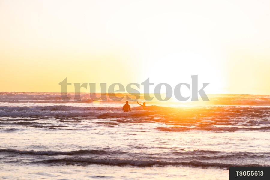 Man and his sister swimming at sunset