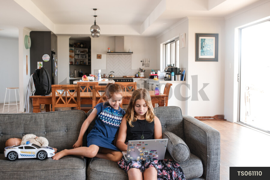 Sisters with laptop on sofa
