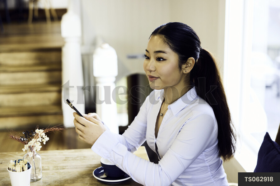 Woman working remotely with smartphone in cafe