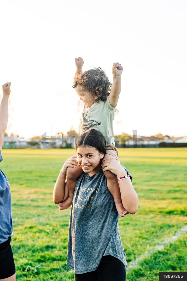 Girl giving piggyback ride to her brother in park