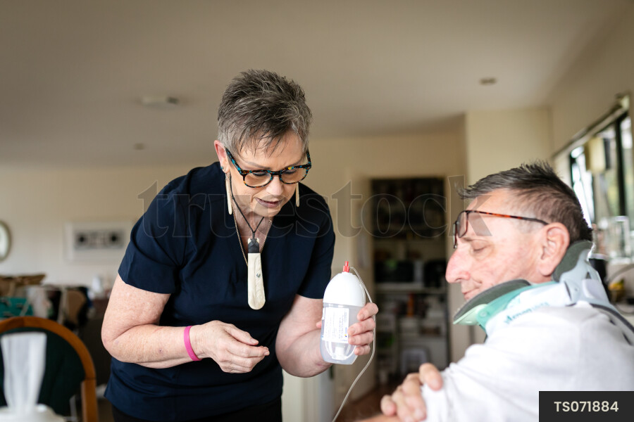 Health carer giving medicine to patient with neck brace