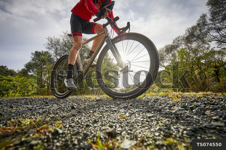 TS074550 Man riding bicycle on unpaved path by Matt Crawford - Truestock