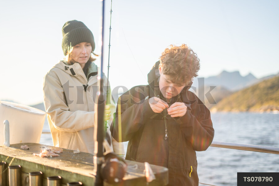 Boy fishing on boar with his mother