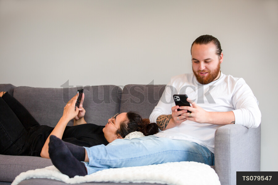 Couple Using Phones on Couch