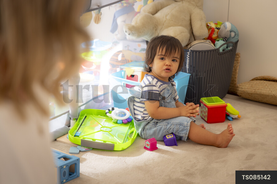 Mother by baby boy with toys in playroom
