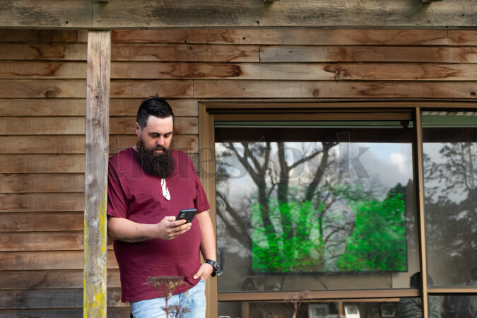 Man Using Phone on Porch