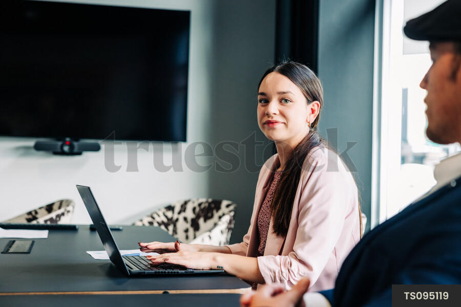 Businesspeople with laptop during meeting in boardroom