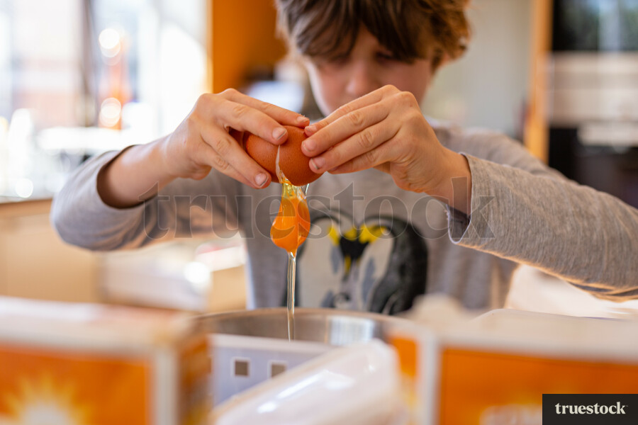 Child cracking an egg and baking