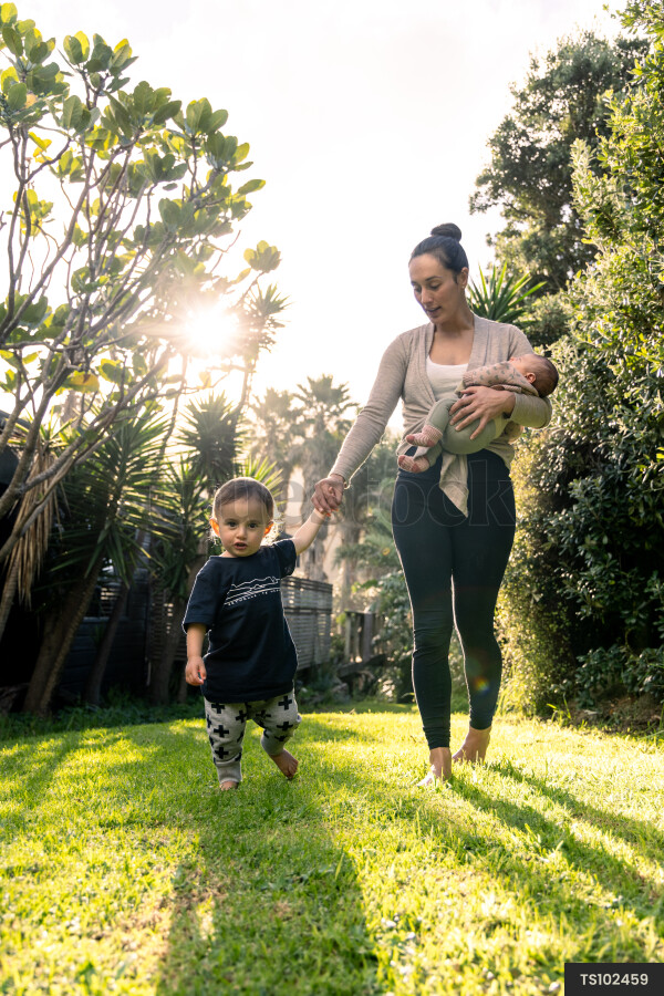 Mother and children holding hands while walking in garden