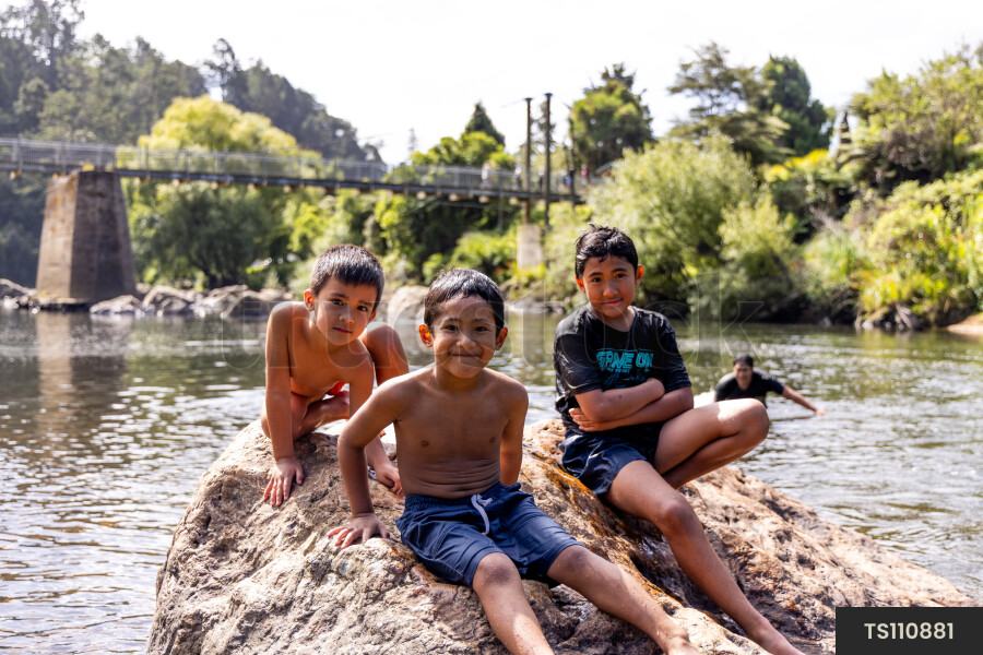Boys sitting on rock by river