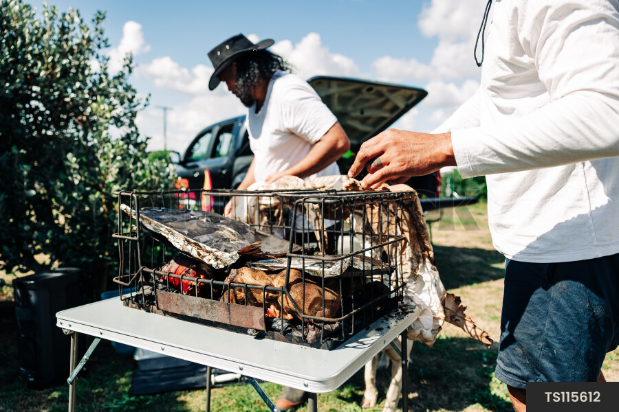 Father and son with meat in grill basket in back yard