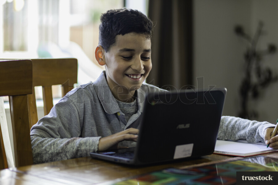Boy sitting at Table using a Laptop