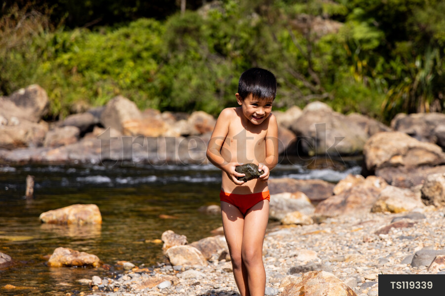 Smiling boy with stone by river