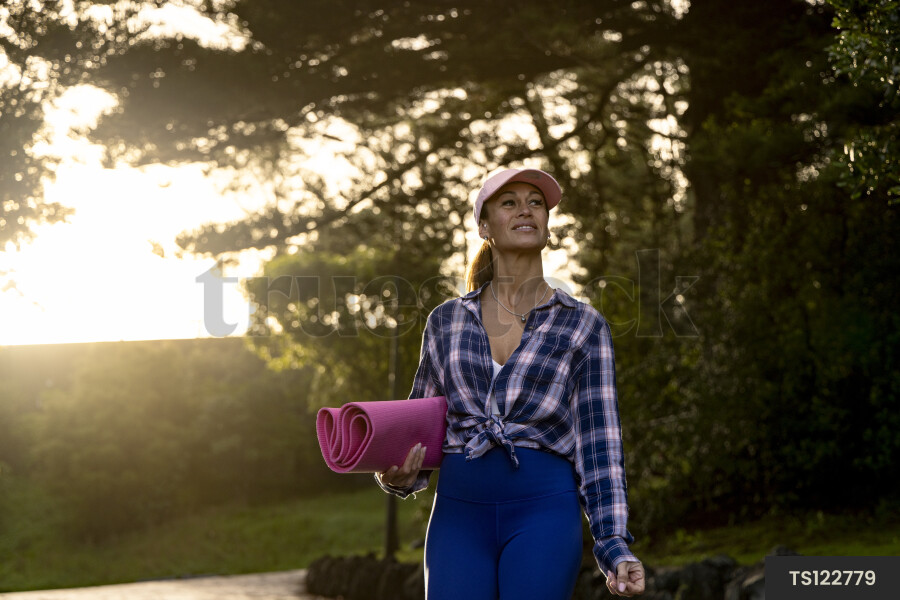 Happy woman with yoga mat in nature
