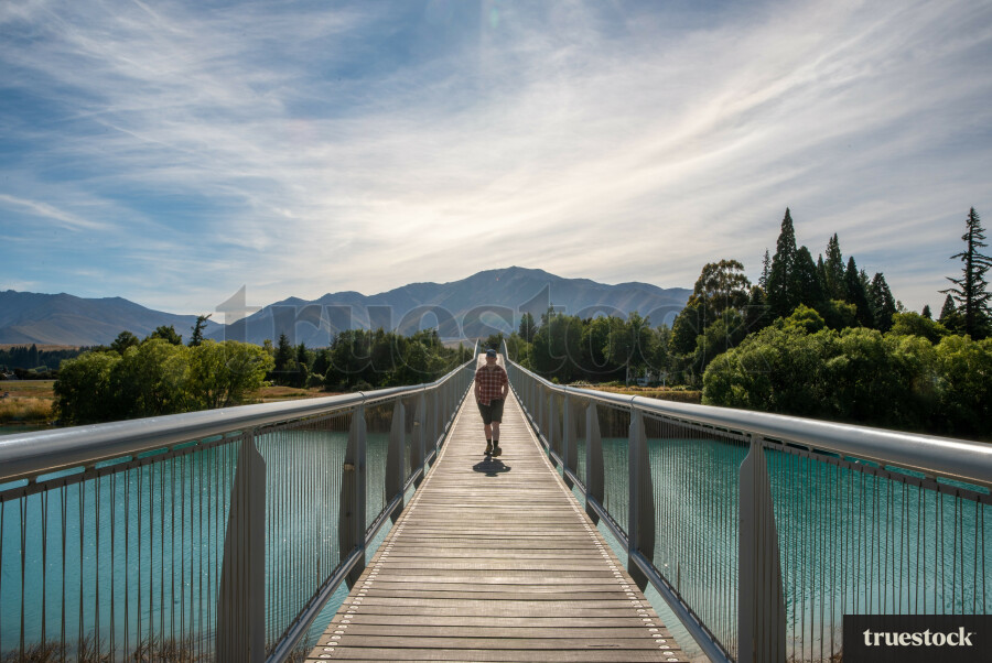 Person walking over a bridge on Lake Tekapo