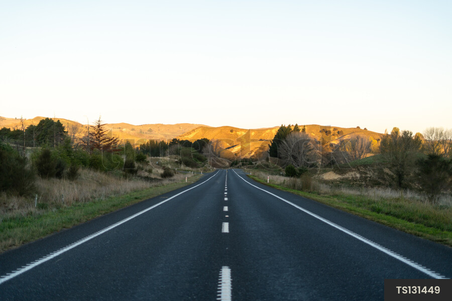 Road through countryside in front of mountain