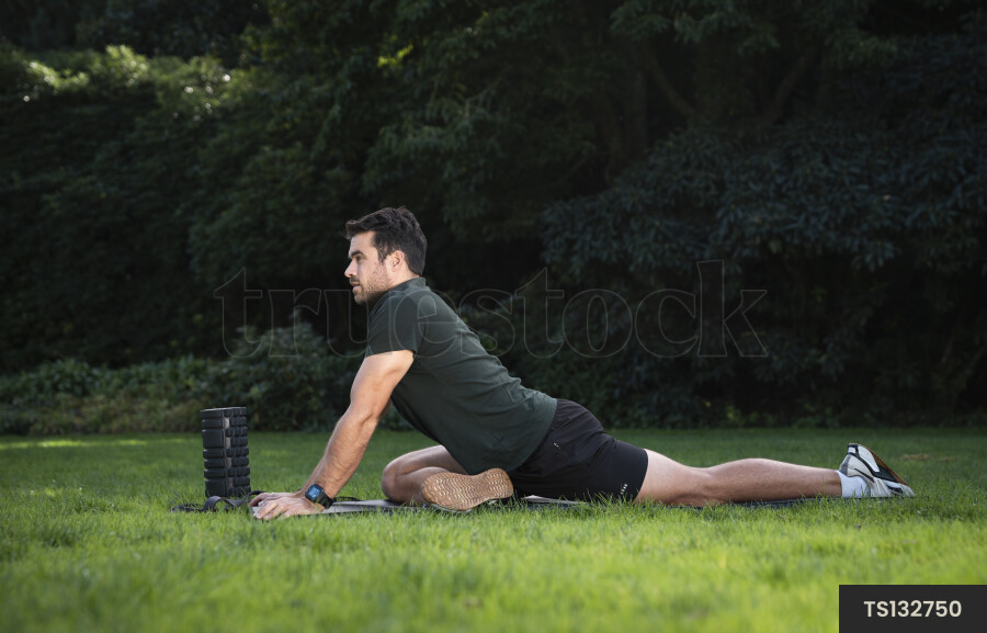 Man stretching on exercise mat in park