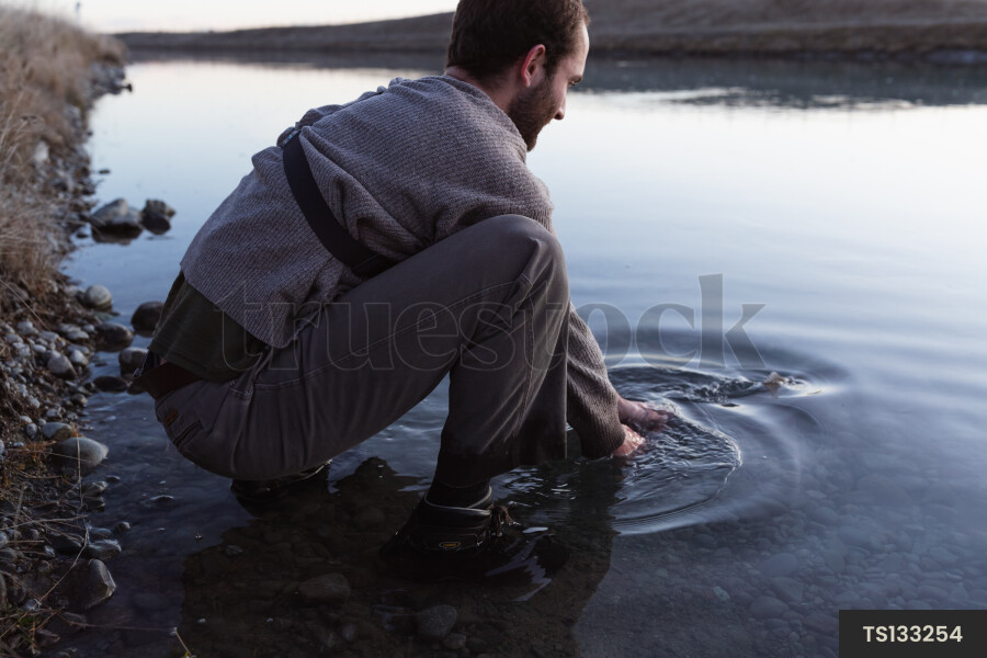 Man crouching in river