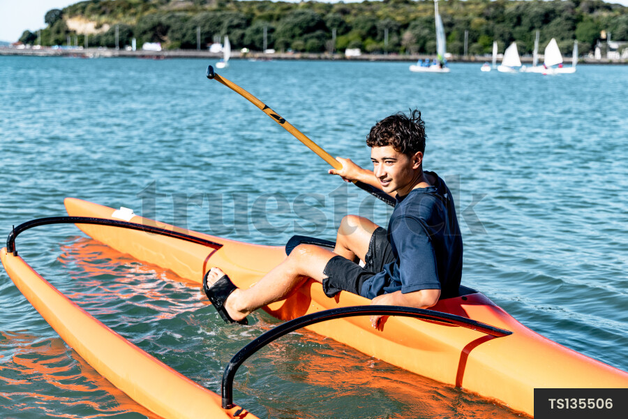 Teenage boy paddling on canoe in Okahu Bay