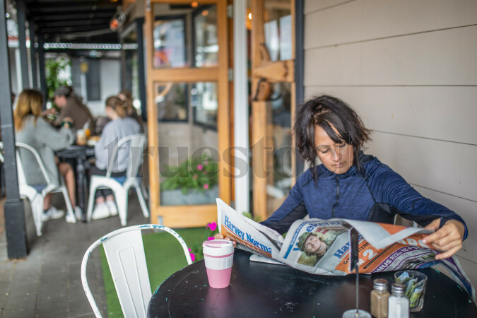 Woman Reading Newspaper at Cafe