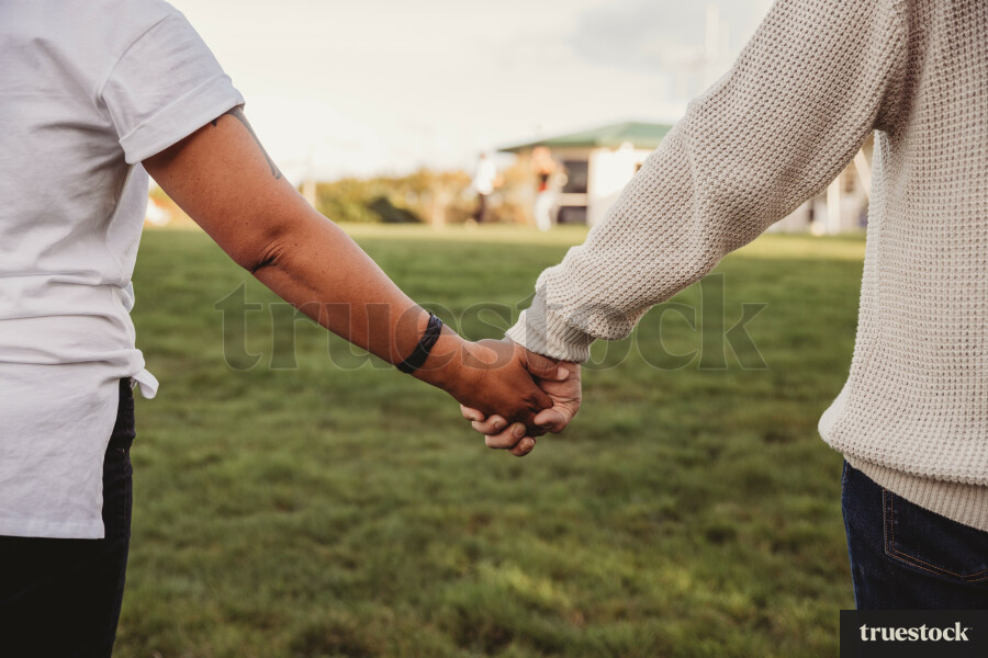 Rear view of married loving couple holding hands standing in the backyard