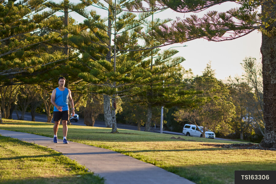 Tongan man walking on sidewalk in park