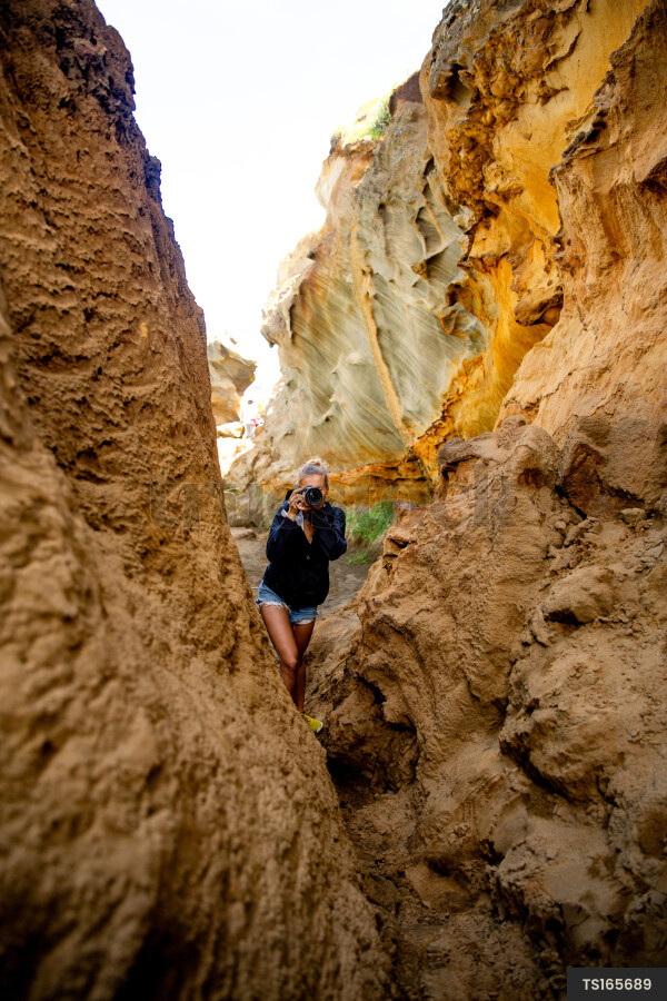 Woman with camera by cliffs