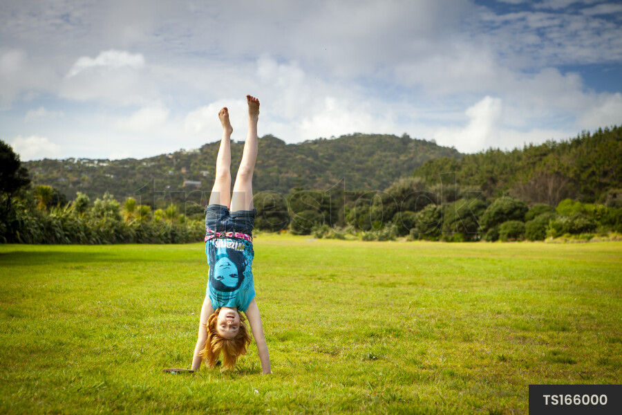 Young Girl Doing Cartwheel on Grass