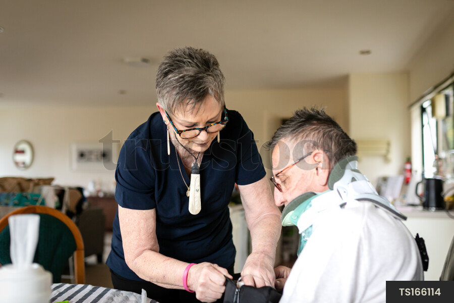 Health carer giving medicine to patient with neck brace