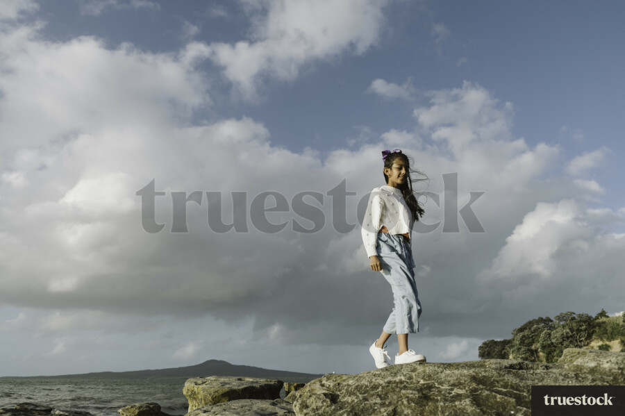 Young Girl Standing on Rocks at Beach
