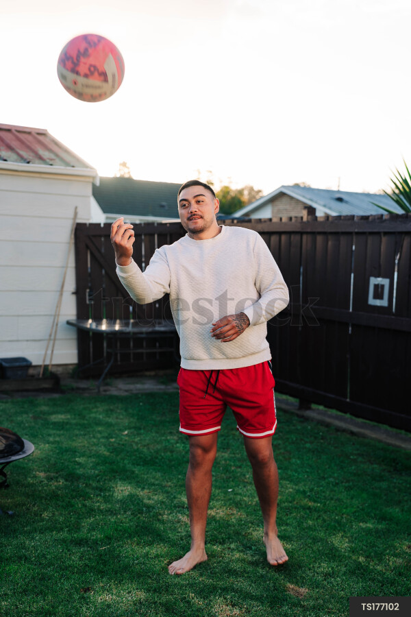 Maori man throwing ball in garden