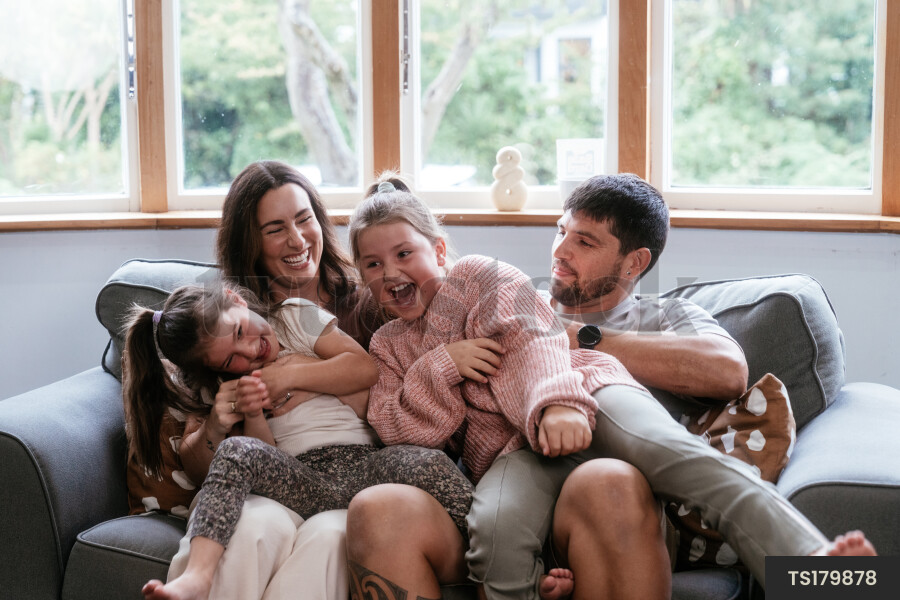 Happy family laughing on sofa in living room