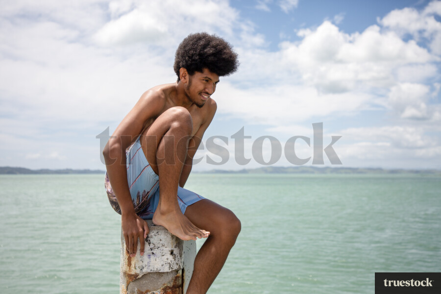 Teen Boy Sitting on Wharf Post