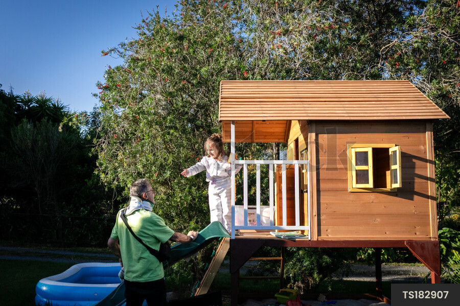 Man playing with granddaughter in playhouse