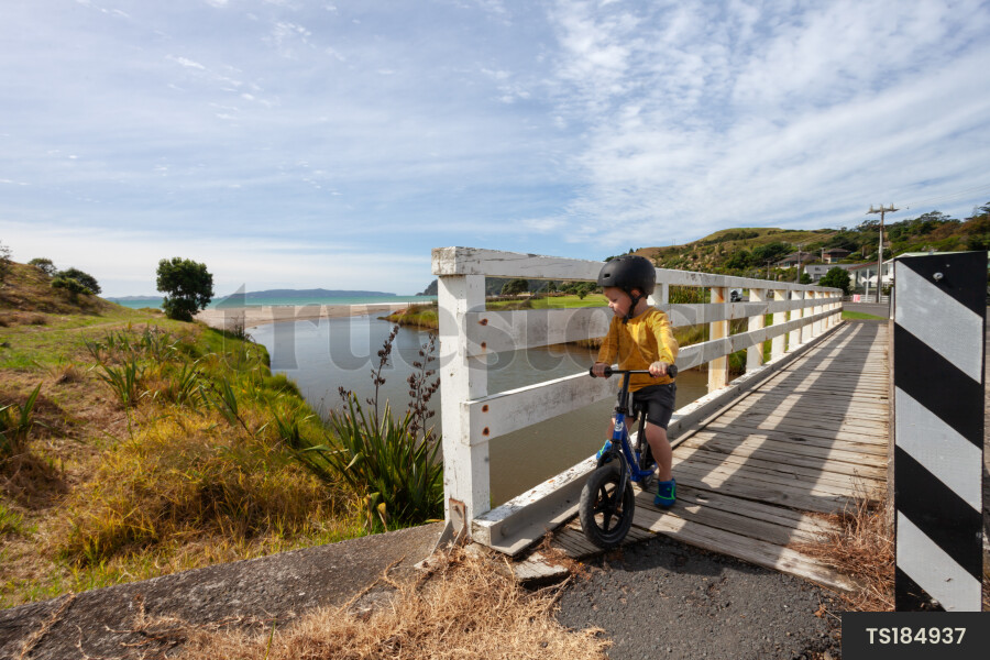 Boy riding bicycle on bridge