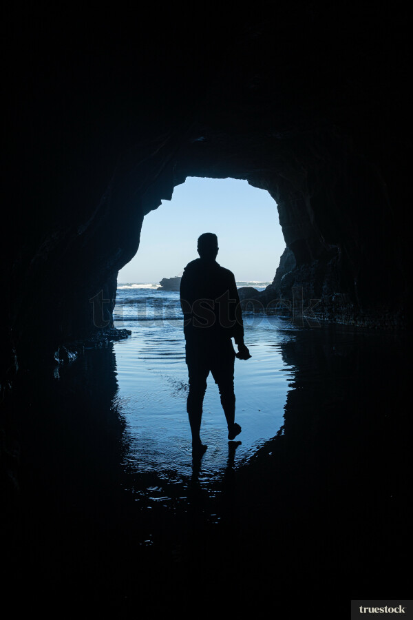 Man Standing in Cave at Beach